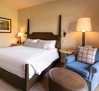 image-card-package-comedy-396x364 Room with a king size bed, chair, and ottoman.