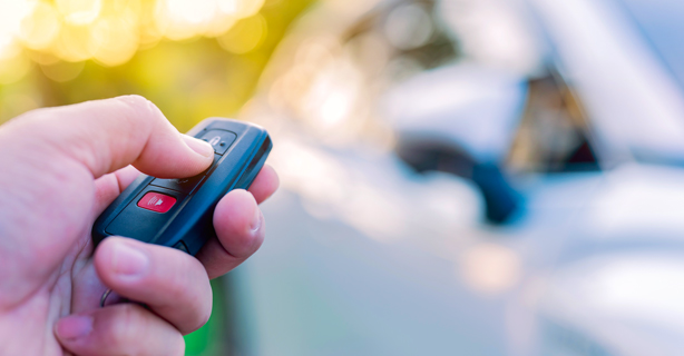 Person's hand pressing the lock button on their car key.