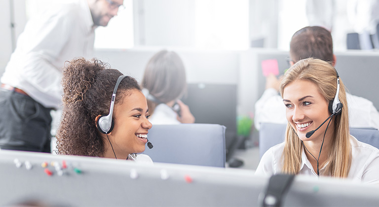 Two women on headsets working on computers