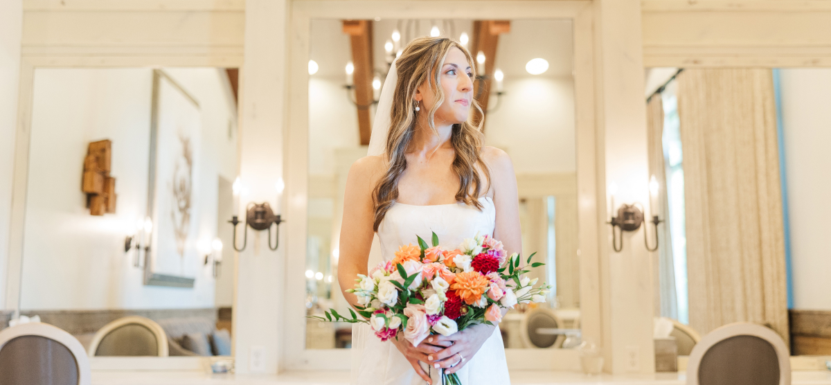 Bride holding a bouquet of flowers with mirrored wall behind. 