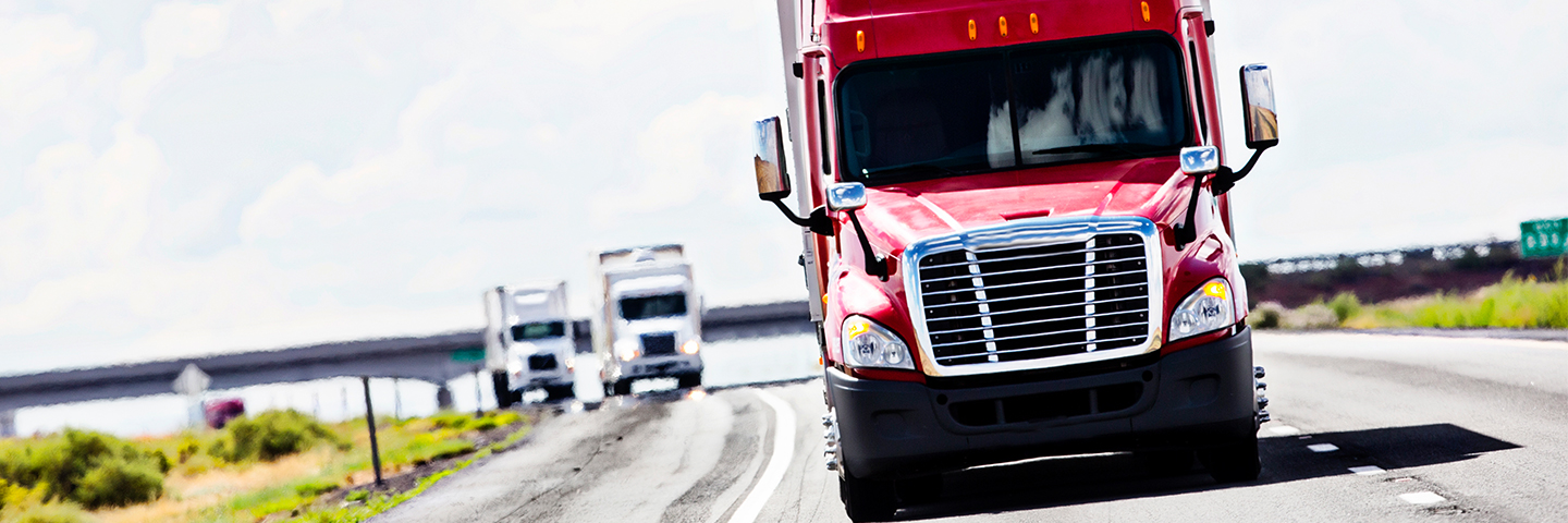 Red semi trailer truck driving down highway