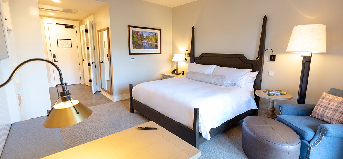 carousel-king-terrace-2-1200x556 King bed with a chair and ottoman and a desk.