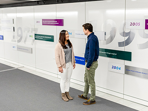 Two people talking near the Sentry timeline wall at Sentry home office.