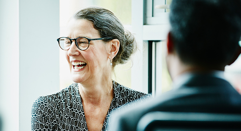 Woman in glasses laughing in meeting with someone