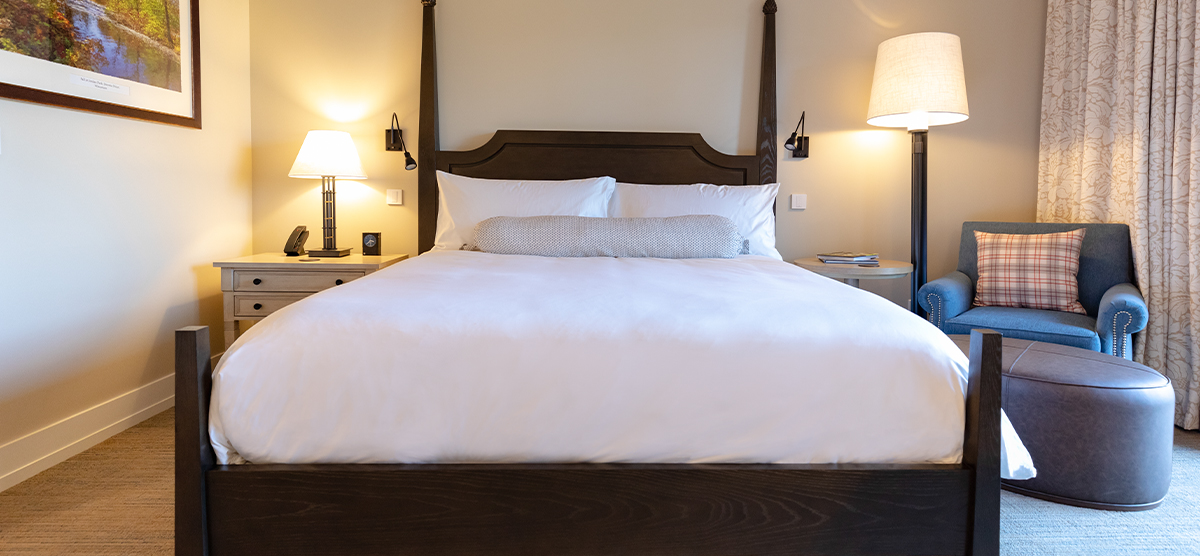 Bed with bedside tables and a chair in  a King Terrace room at The Inn