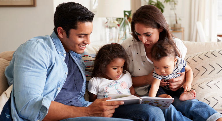 Family of four reading a children's book