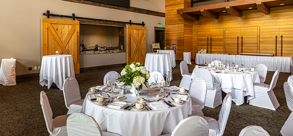 carousel-wedding-venue-atrium-2-1200x556 Atrium room with white tables and chairs and a bar area.