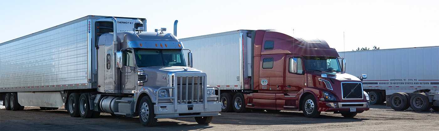 Two semi trucks parked in a lot.