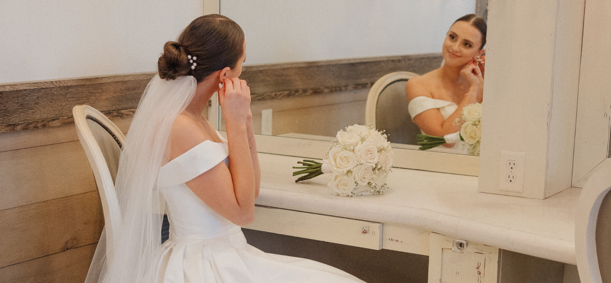 Bride fixing earing and looking into a mirror in the SentryWorld salon. 