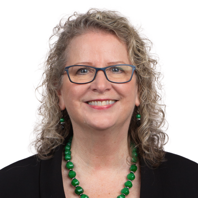 Woman with glasses and curly shoulder length hair. 