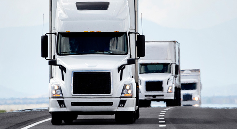 White semi trailer trucks driving down highway