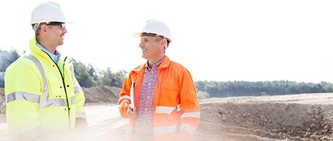 Two workers in safety gear in field