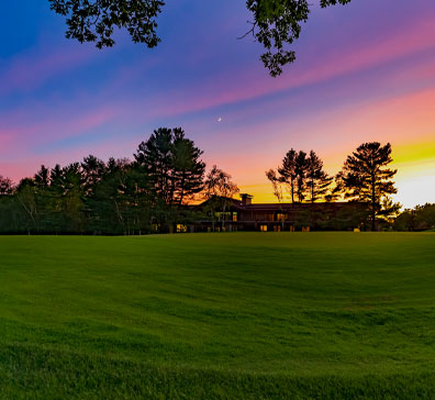 View of The Inn at SentryWorld from the golf course with a sunset sky