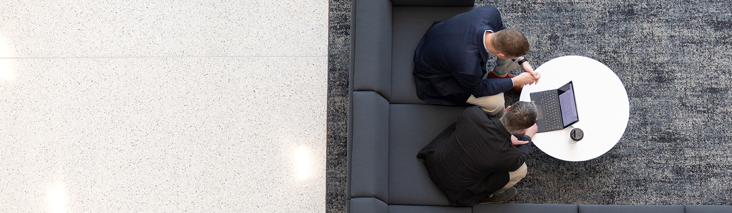 two men sitting on couch working on laptop