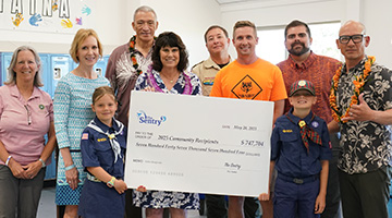 Adults and children standing around a large donation check. 