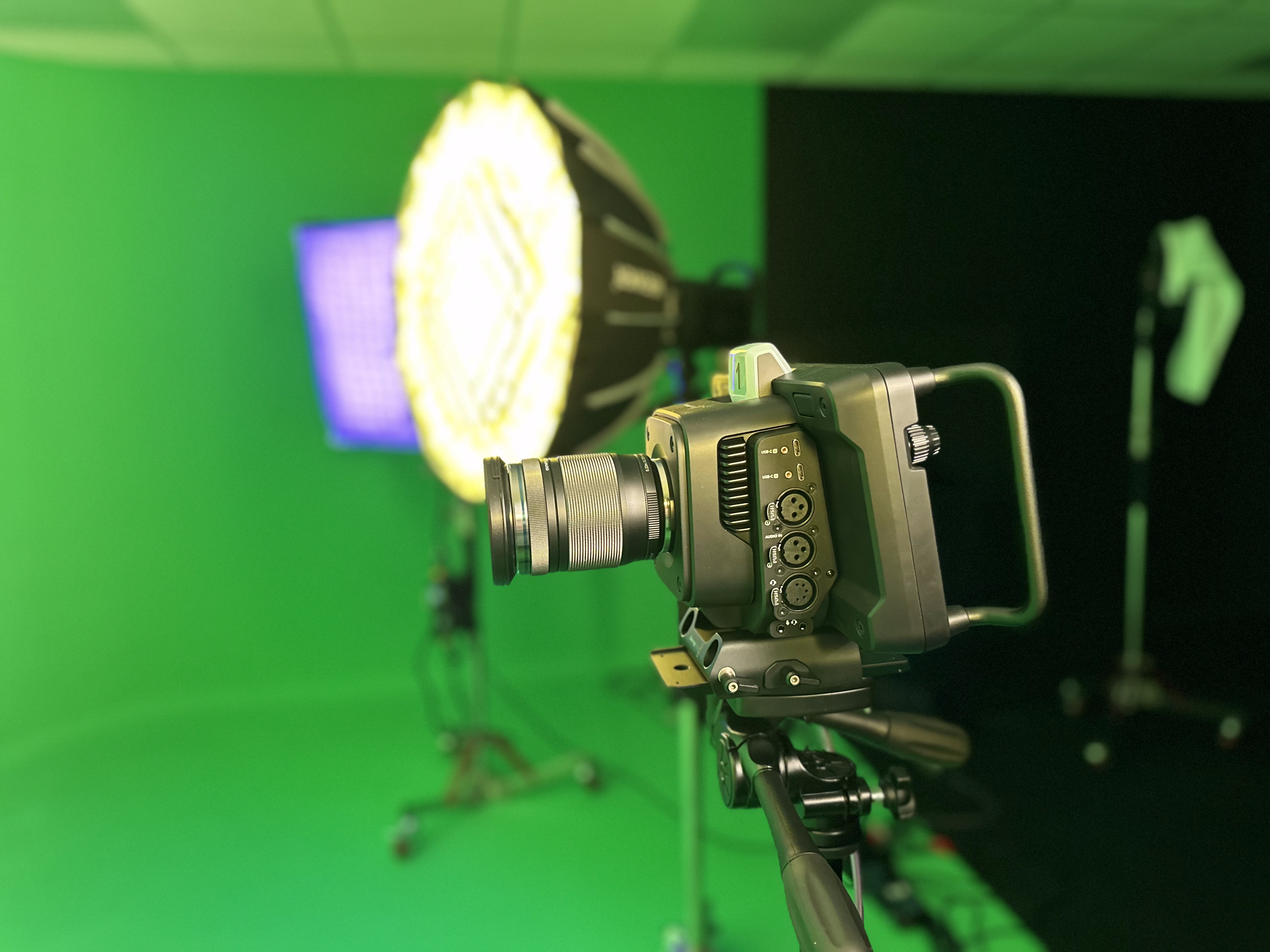 Cinema camera on a tripod facing the green screen