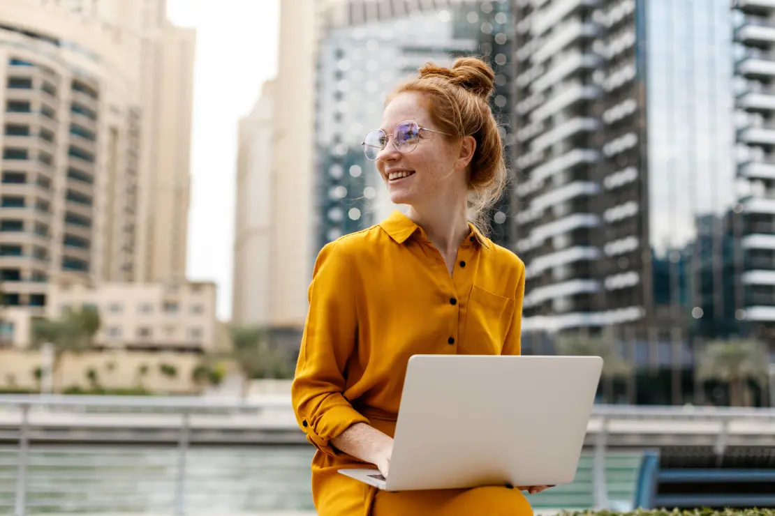 Woman holding a laptop working outside