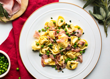 https://images.ctfassets.net/xhwawwjr0s5c/2hMFta4nQgaiWO8MAmWi6o/e8c438b48aa39600cf7a3bbd7b012888/05_PROSCIUTTO-_-CHEESE-TORTELLONI-WITH-HAM_-PEAS-AND-SAGE.jpg?fit=thumb&w=420&h=259