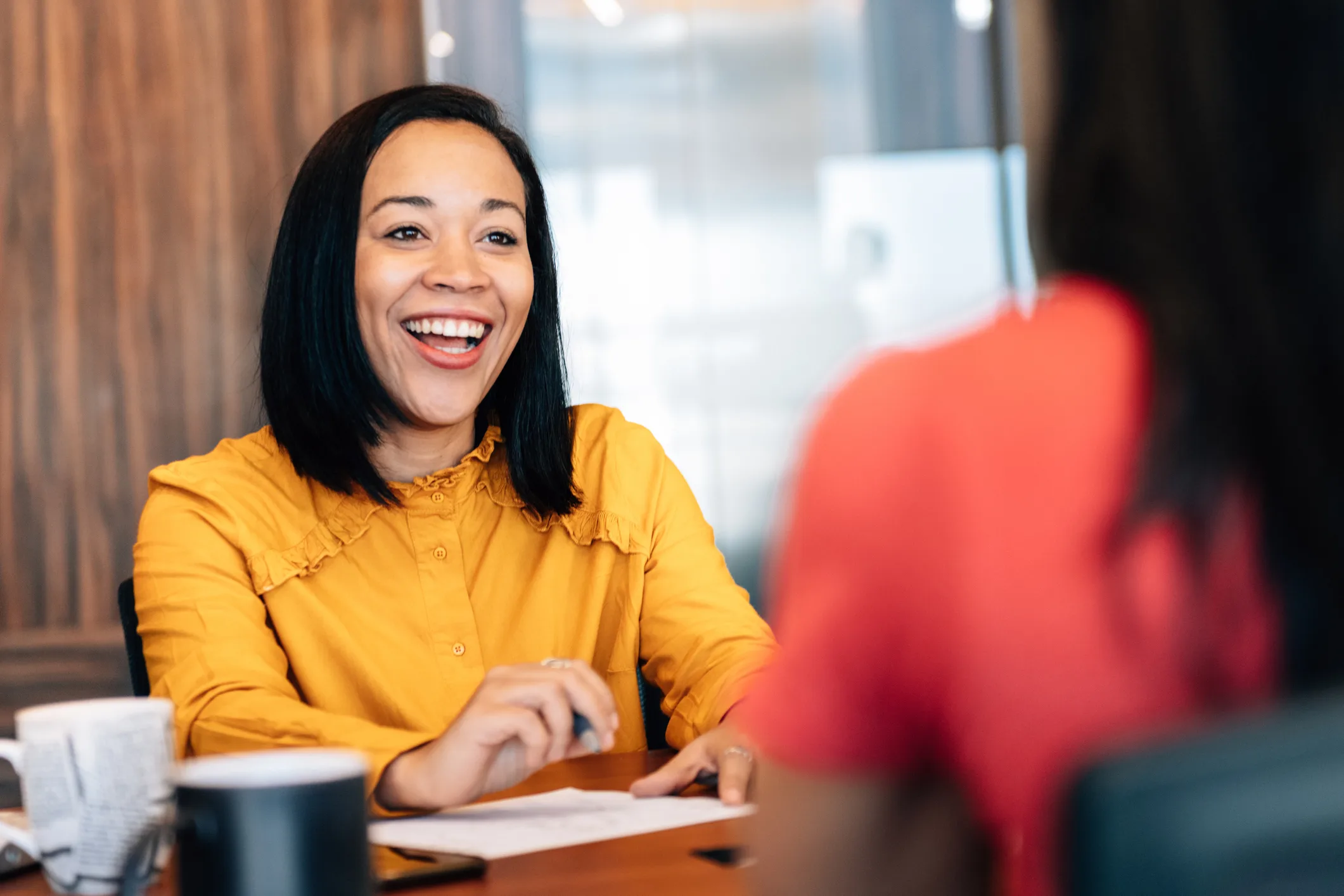 Smiling woman in customer service wearing a mustard yellow blouse 