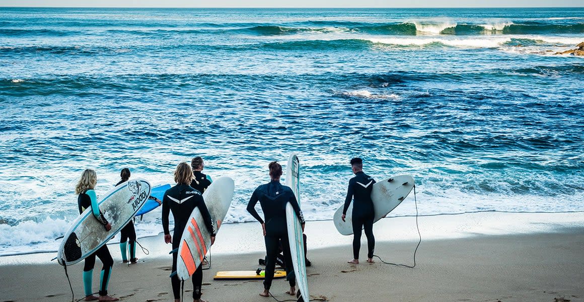surfers facing the ocean
