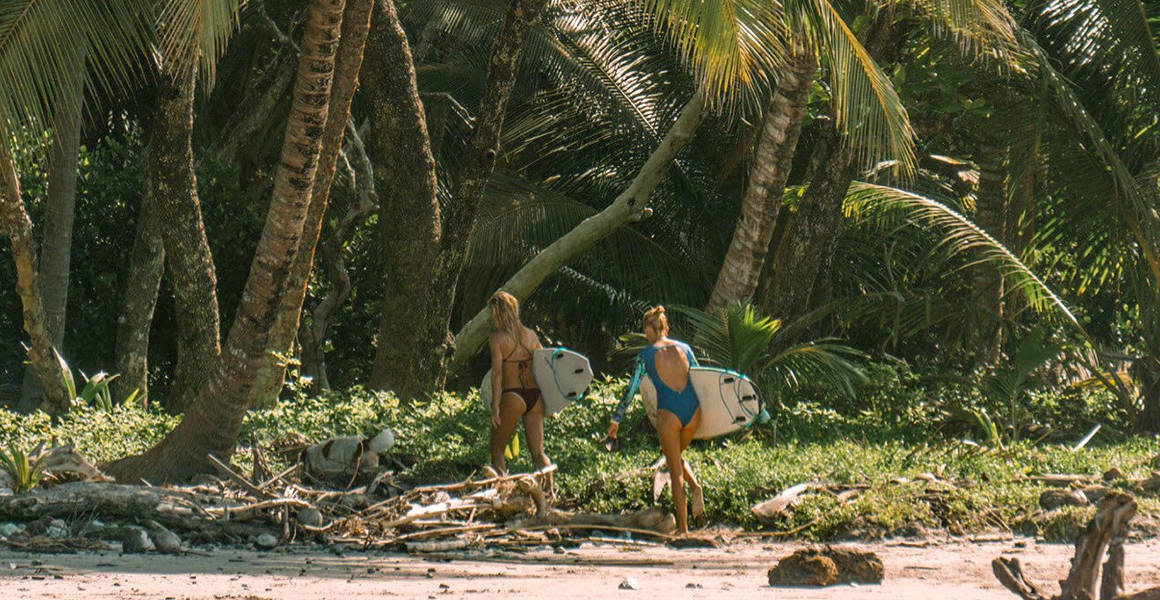 girls in the jungle carrying surfboards costa rica