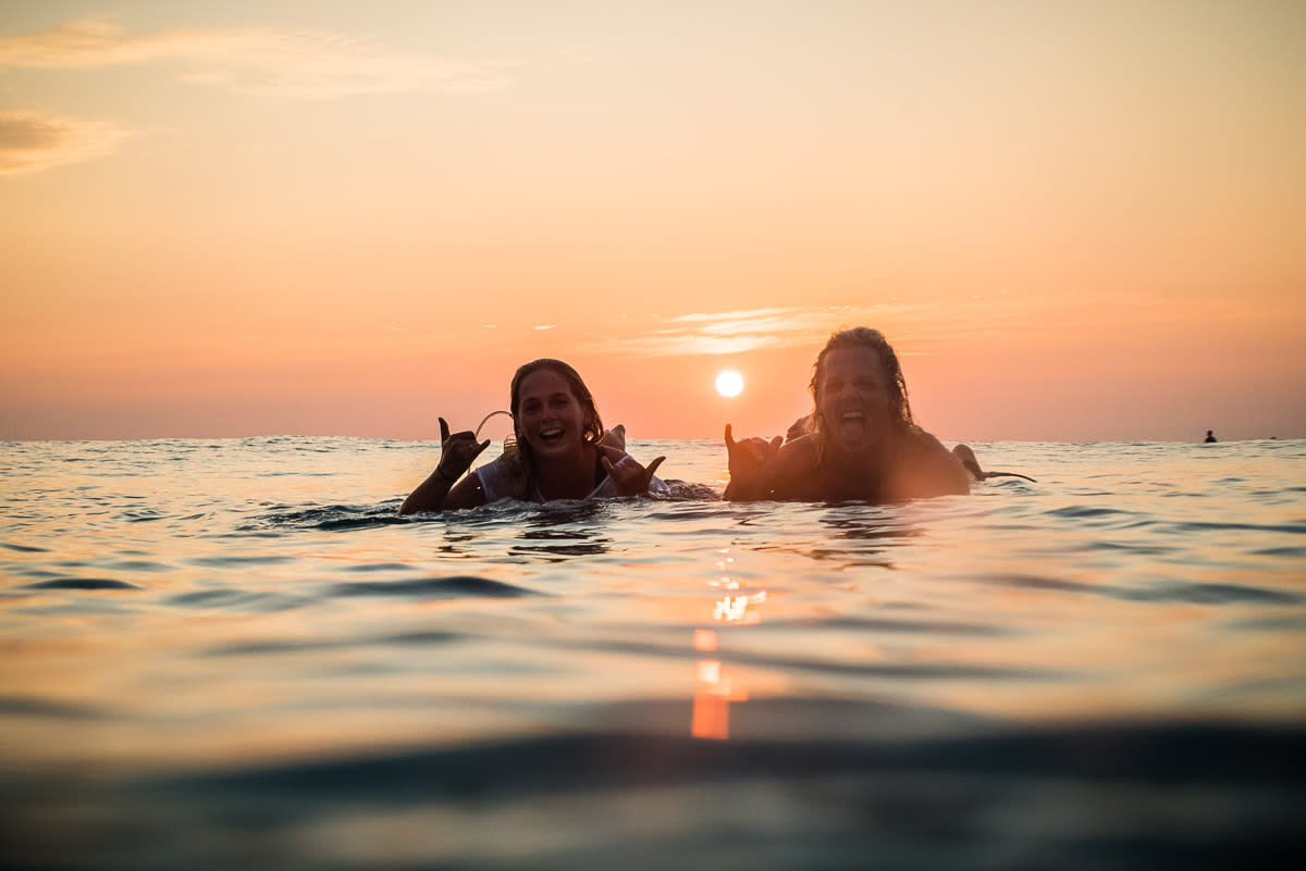 Surfers in sunset lying on their boards