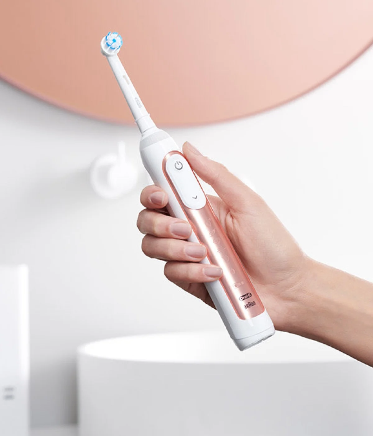 Frau, die eine roségoldene elektrische Zahnbürste der Oral-B Genius X Series hält 