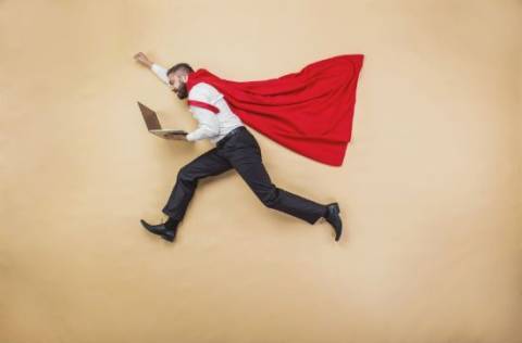 Man with red cape holding laptop