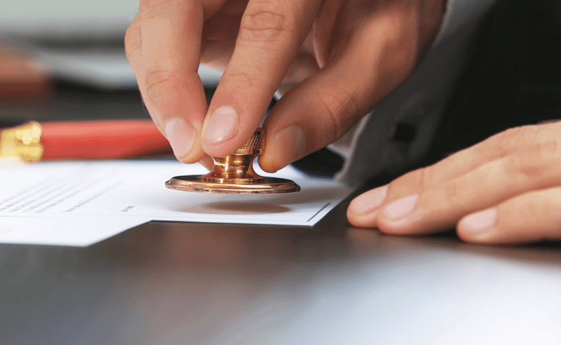 close up of hand stamping approval on paper