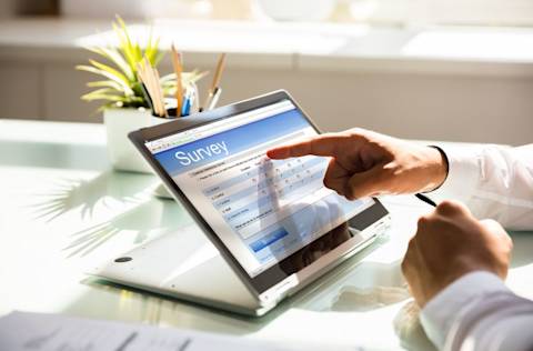 Close-up of a businessman's hand filling online survey form on laptop in office