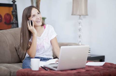 Happy young woman working from home and talking to a customer