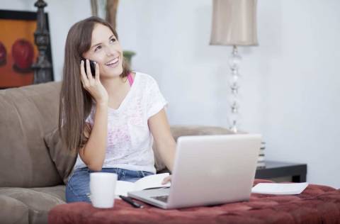 Happy young woman working from home and talking to a customer