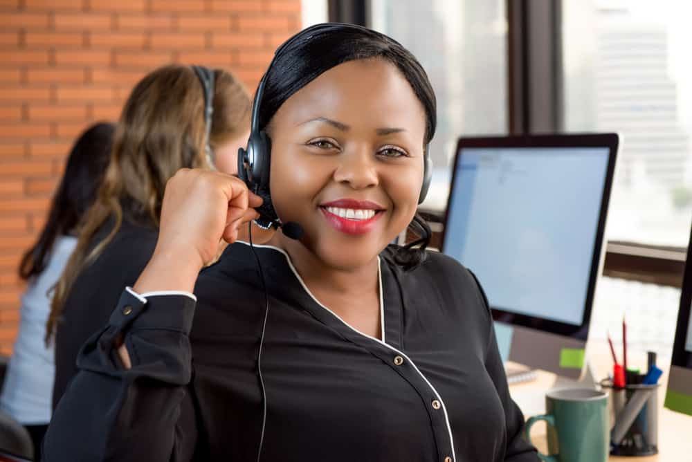 Smiling beautiful black businesswoman working in call center as a customer service agent with her multiethnic team