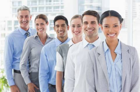 Happy business people looking at camera in a row in office