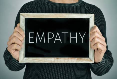 Man holding a chalkboard with the text empathy
