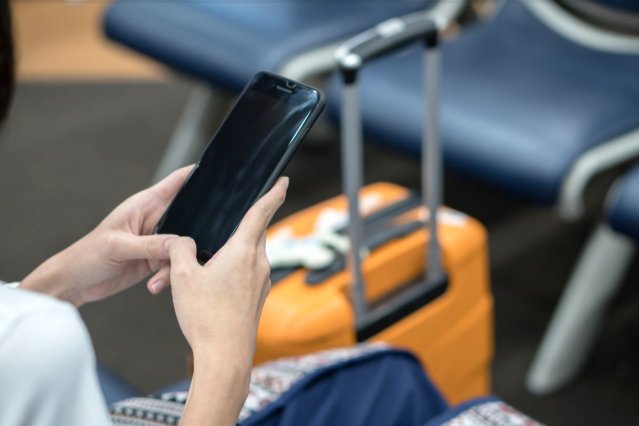 Young Asian traveler woman, using smartphone at airport