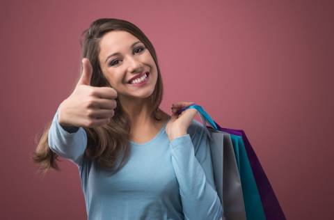 Happy smiling woman thumbs up shopping and holding bags