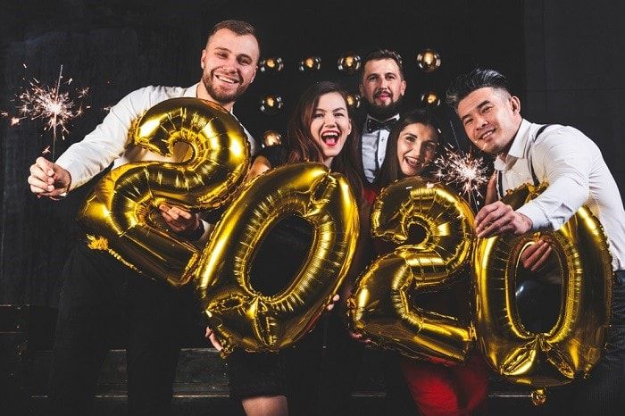 Group of people with sparklers and gold 2020 balloons.