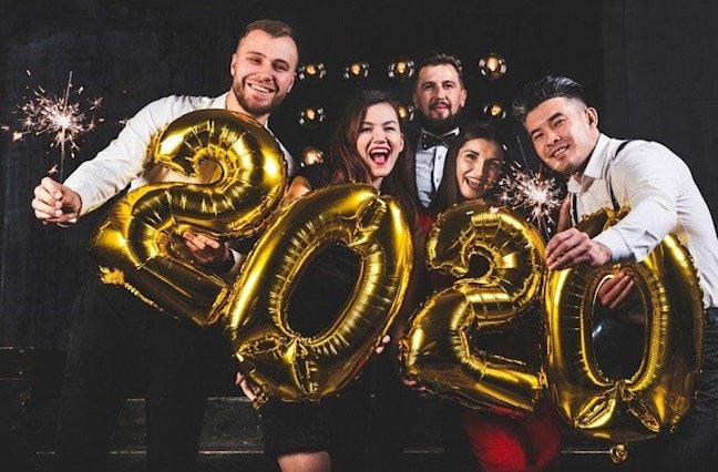 Group of people with sparklers and gold 2020 balloons.