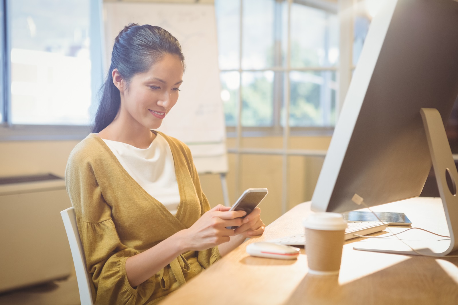 business woman at desk texting on phone
