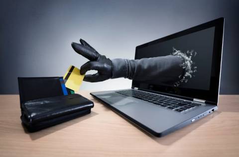 cybersecurity thieves hand breaking through laptop screen to steal credit card