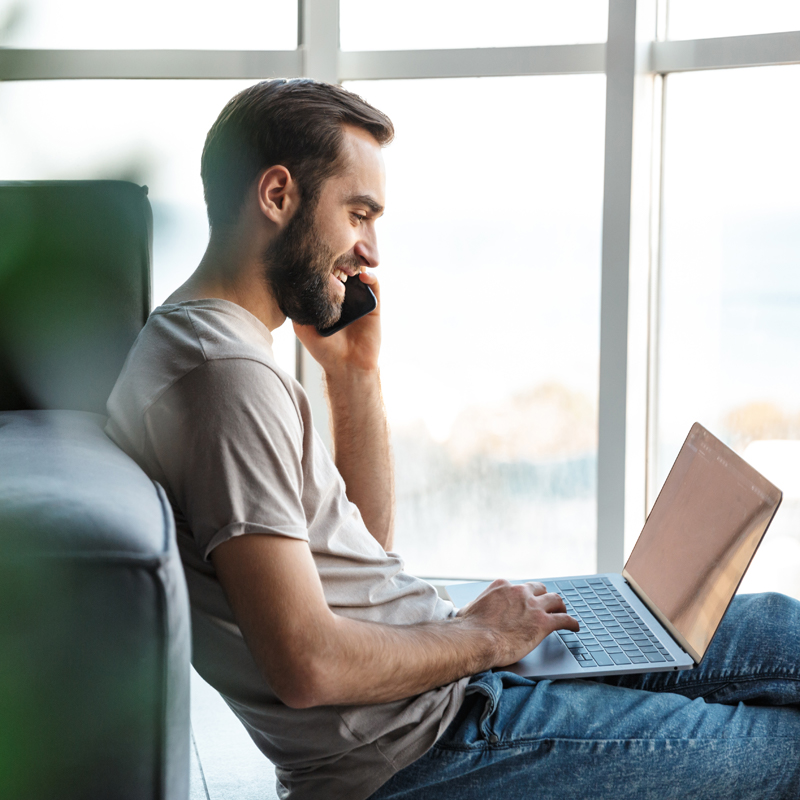 Man talks on phone while using laptop
