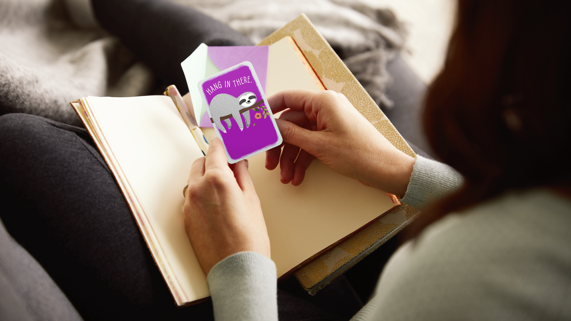 Person holding Hang In There card over open book