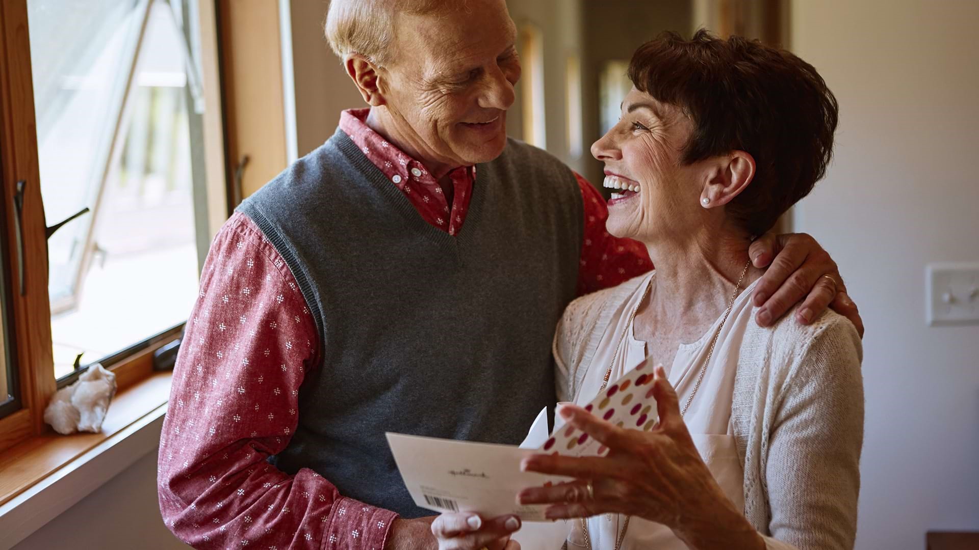 Two older people smiling over a card ARTICLE HERO IMAGE