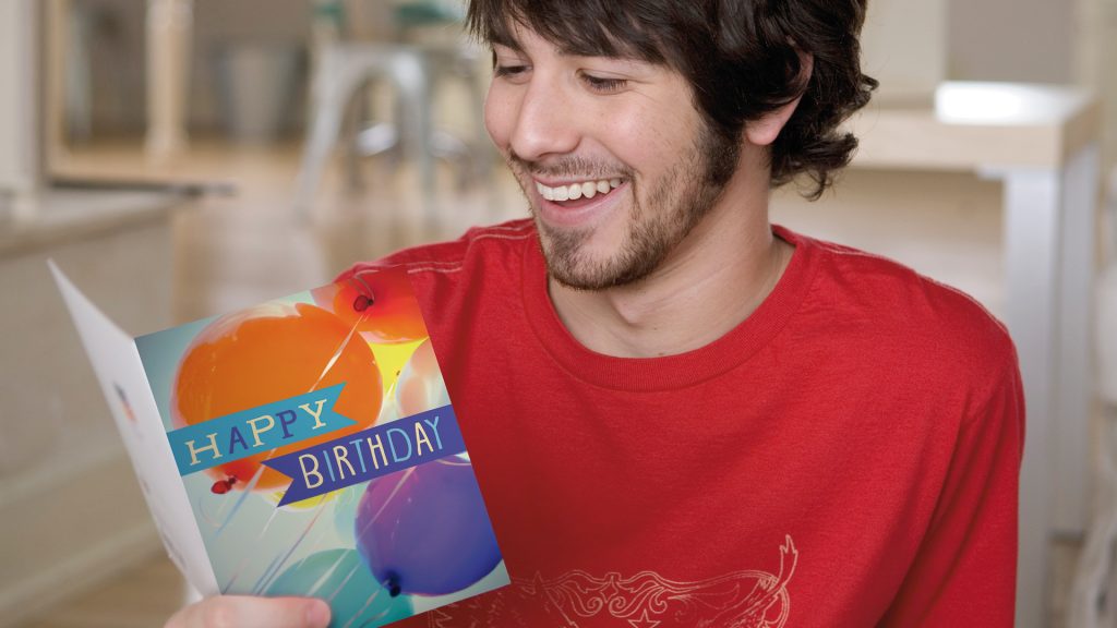 L male red shirt smiling at birthday card
