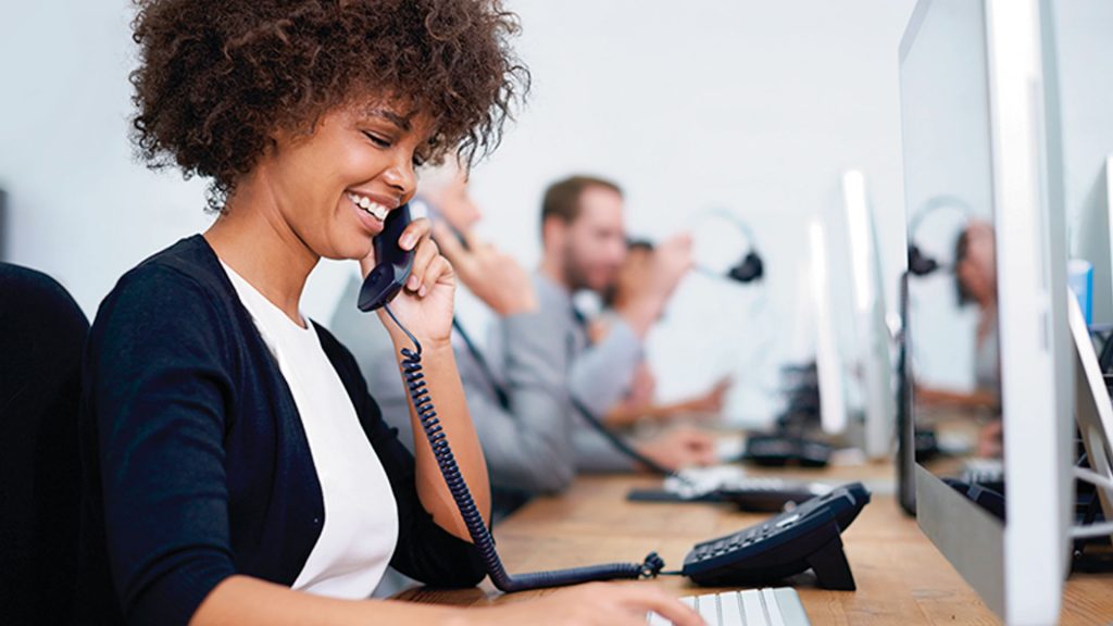 L female smiling on phone at desk