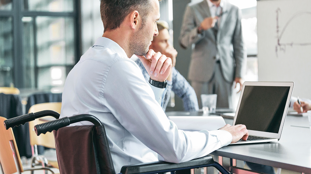 Male in wheelchair on laptop in meeting