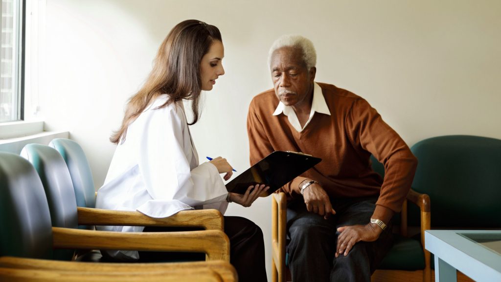 L female explaining medicare benefits to male in waiting room