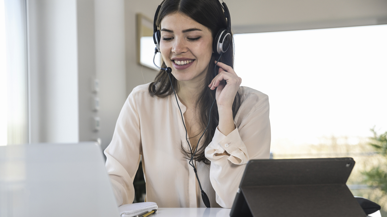 Female wearing headset with laptop and tablet working