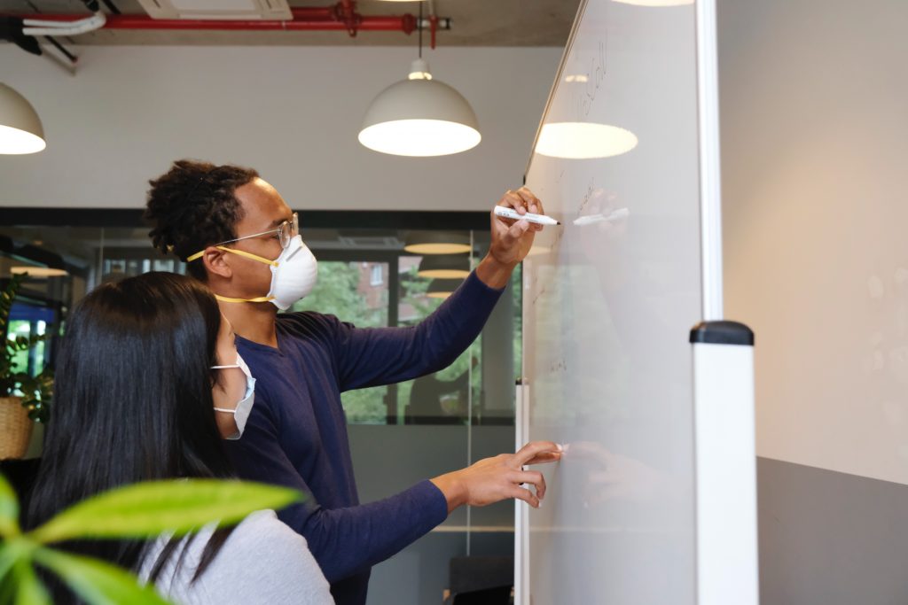 Masked Coworkers Writing on White Board